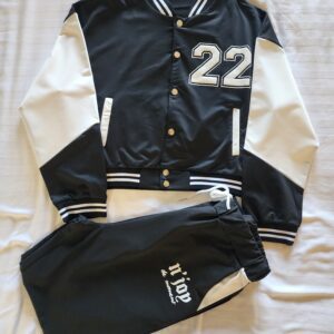 Black and white varsity jacket with matching pants laid flat.