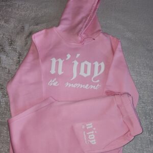 Pink hoodie and sweatpants set with white text on a gray floor.